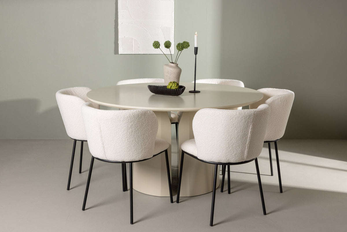 Zwei weisse Esszimmerstühle mit Boucle-Bezug und schwarzen Metallbeinen neben einem runden Esstisch aus beigem MDF mit ⌀140 cm Durchmesser.