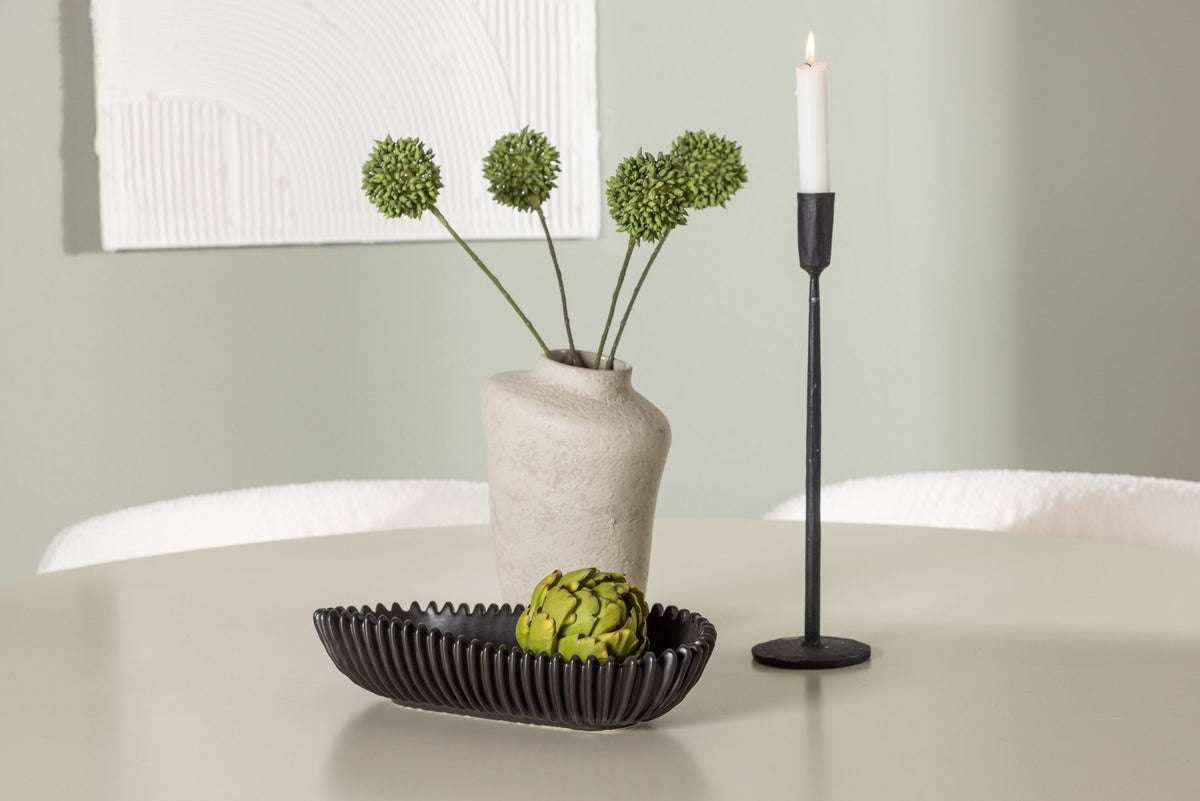 Zwei weisse Esszimmerstühle mit Boucle-Bezug und schwarzen Metallbeinen neben einem runden Esstisch aus beigem MDF mit ⌀140 cm Durchmesser.