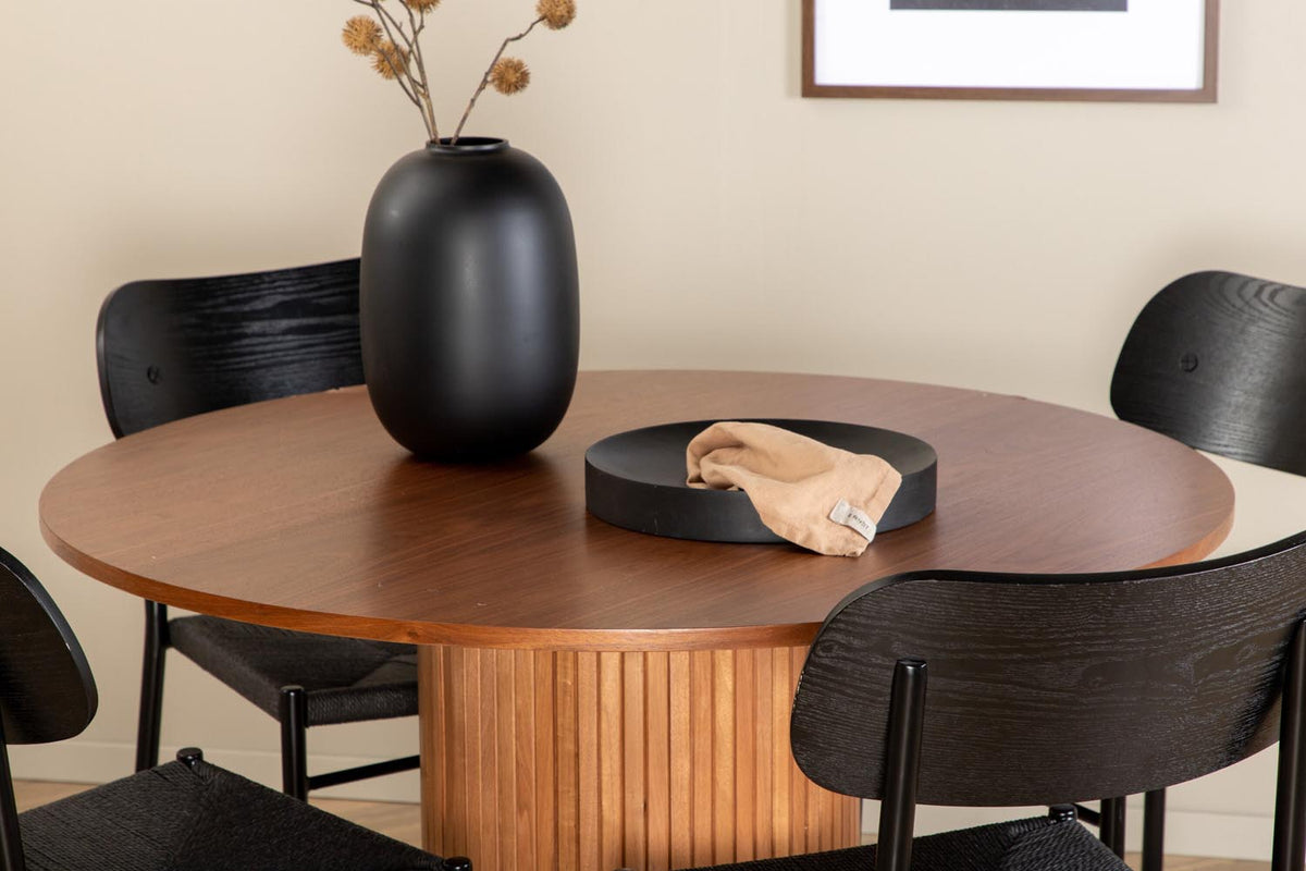 Rundes Esszimmerset Bianca mit Stuhl Polly: Tisch aus MDF und Furnier in Walnuss, vier schwarze Stühle mit Metallbeinen und Seilsitzen.