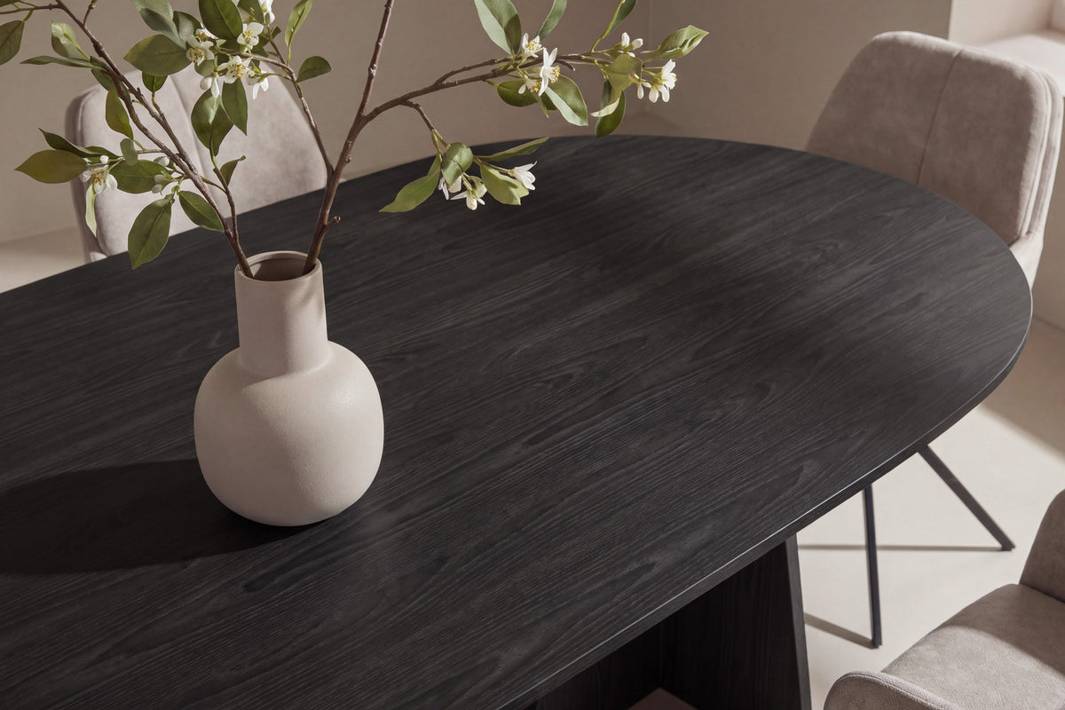 Ovaler Esstisch aus MDF mit Furnier in Schwarz und Metallbeinen, dazu zwei Esszimmerstühle mit braunem Polyesterbezug und schwarzen Beinen.
