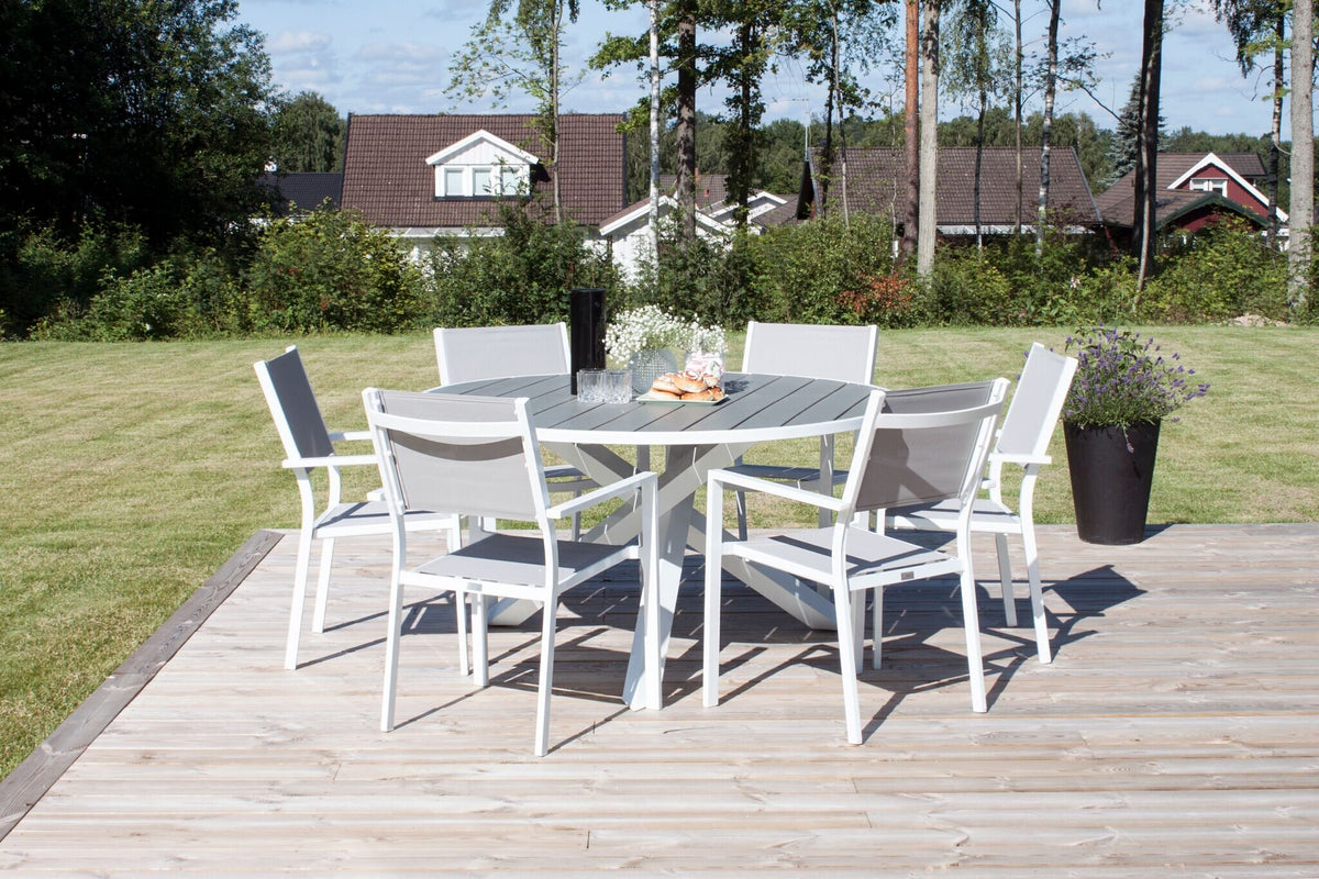 Rundes Outdoor-Tischset Parma, ⌀140 cm, mit sechs stapelbaren Copacabana-Stühlen aus Aintwood in Grau-Weiss, aufgestellt im Garten.