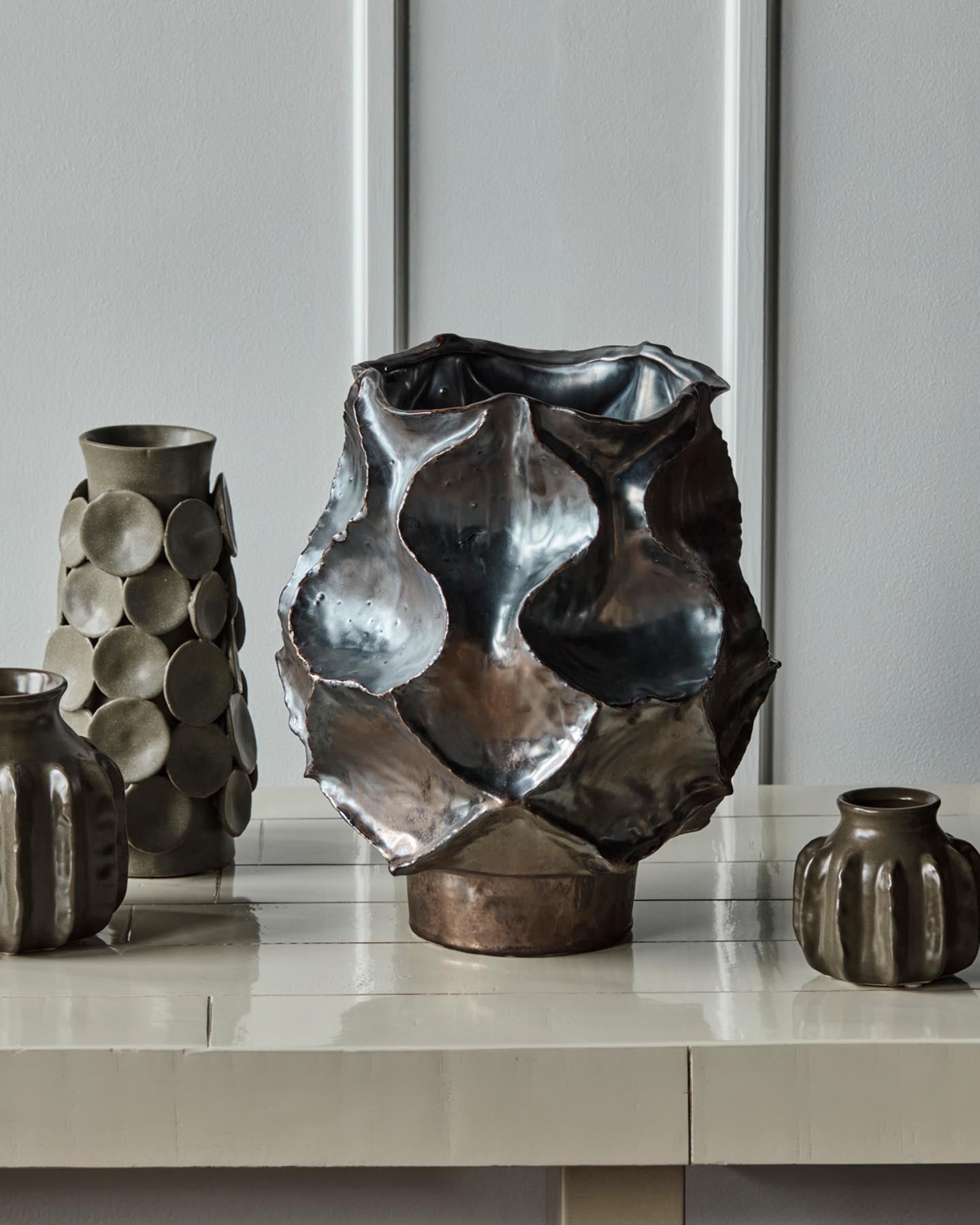 Verleihen Sie Ihrem Zuhause mit der einzigartigen Vase HDWaves von House Doctor einen Hauch von Eleganz. Handgefertigt aus robustem Steinzeug, besticht sie durch ihre antikmetallische Glasur und geschwungene Form. Ideal für Blumen oder als Kunstobjekt.