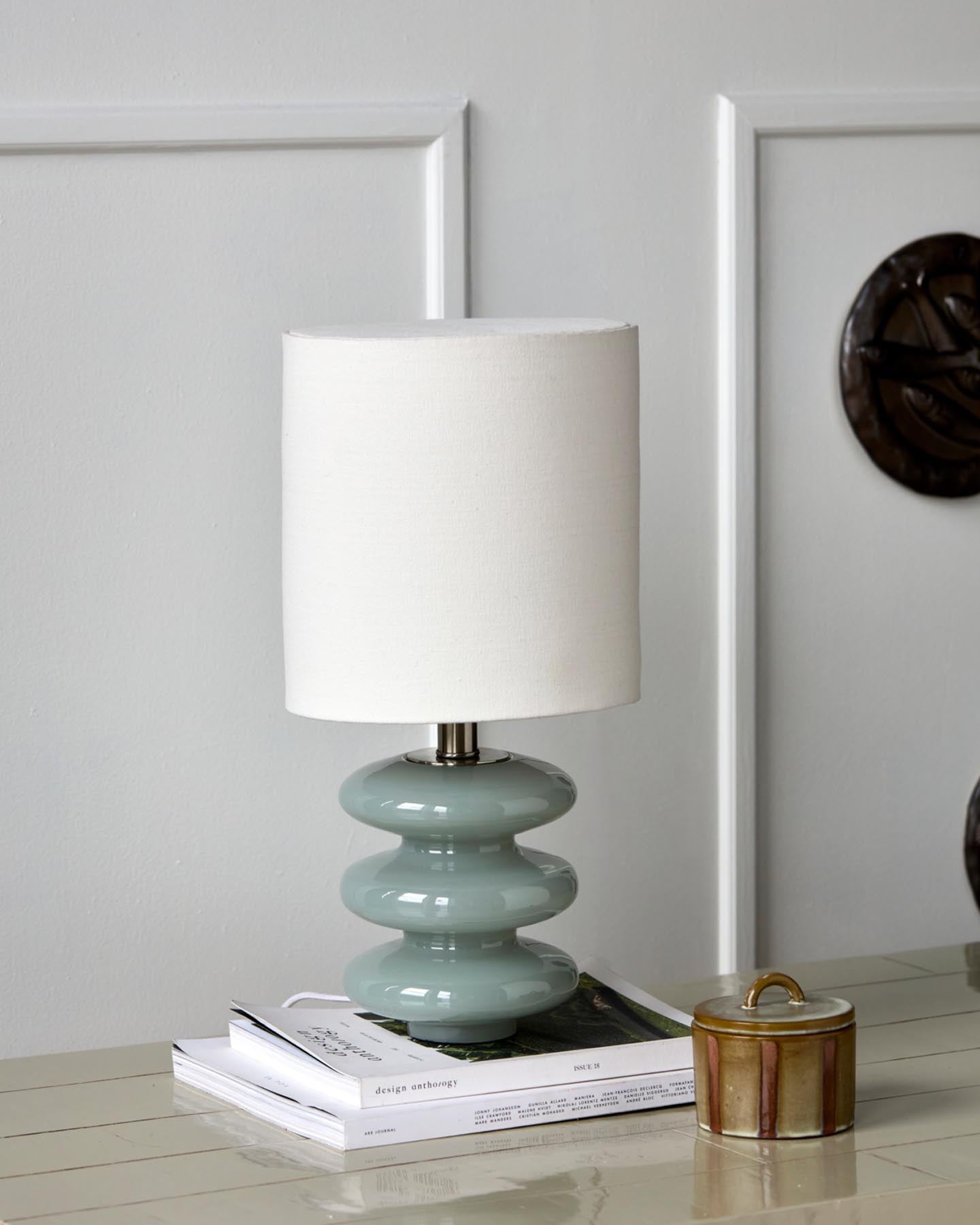 Verleihen Sie Ihrem Raum mit der Tischleuchte HDStep S von House Doctor in Hellblau und Off-White einen Hauch von Eleganz. Handgefertigter Glasfuß und stilvoller Lampenschirm schaffen eine einladende Atmosphäre.