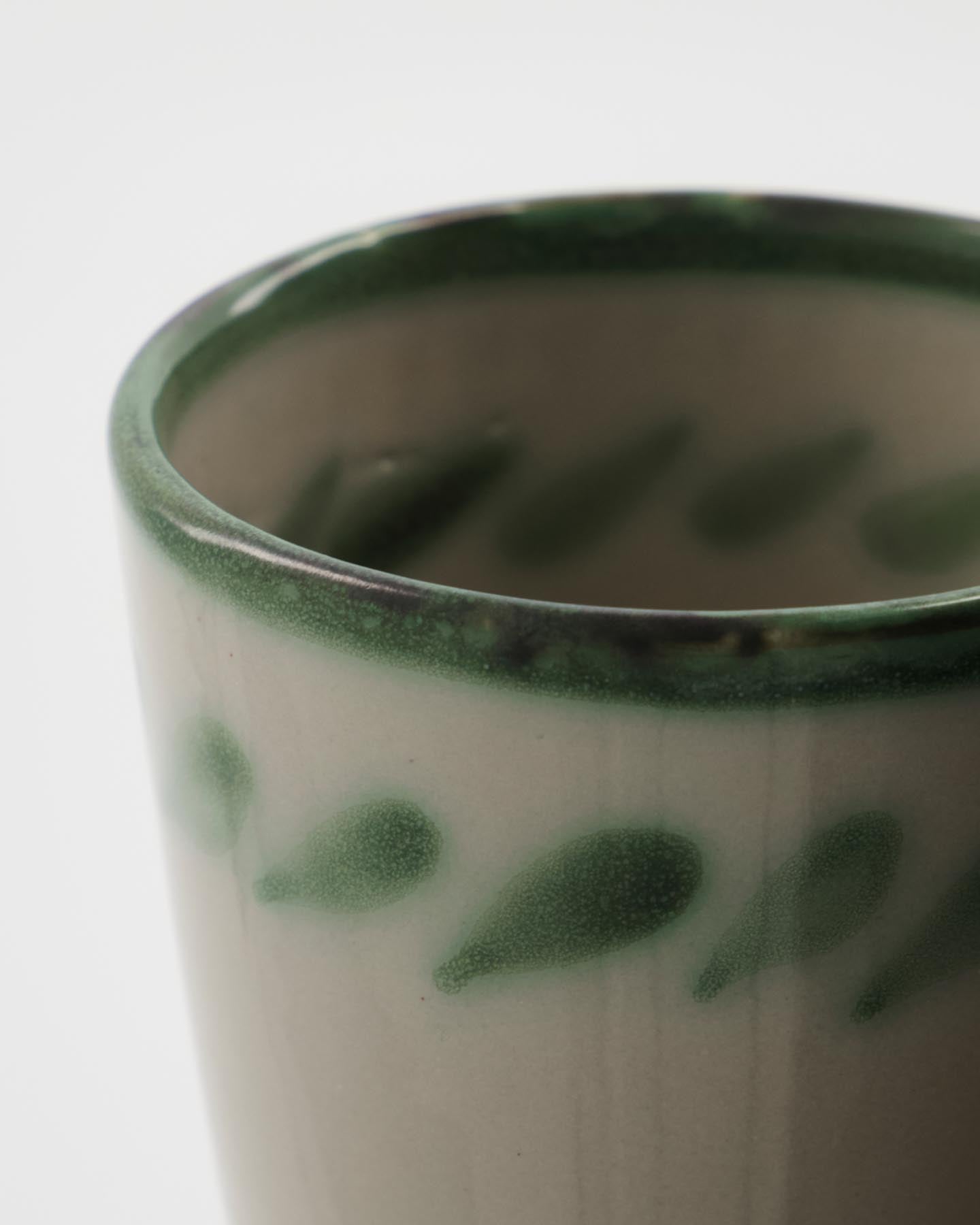 Genießen Sie Ihre Getränke stilvoll mit der HDDiva Tasse von House Doctor – ein rustikales, handgefertigtes Unikat aus Steinzeug mit individuellem, grünem Muster.