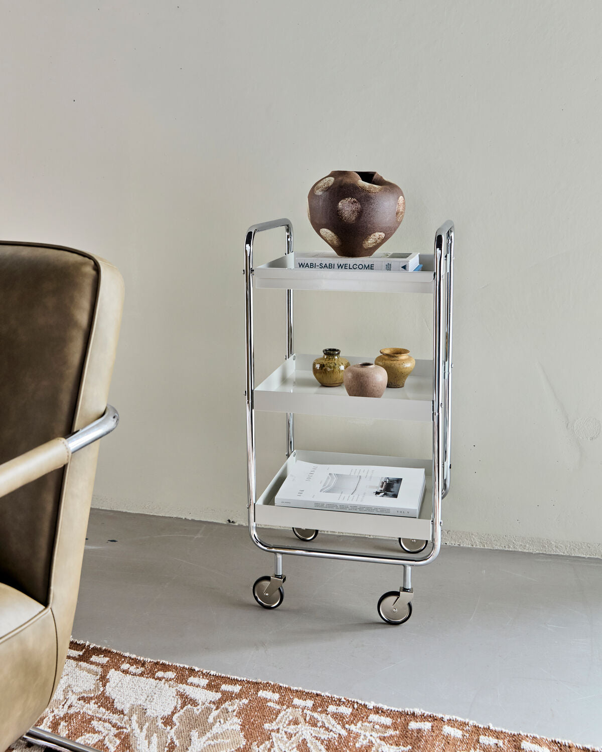 Eleganter Servierwagen in Off-White mit chromfarbenen Akzenten, ideal für stilvolle Präsentationen und vielseitige Nutzung im Wohnraum.