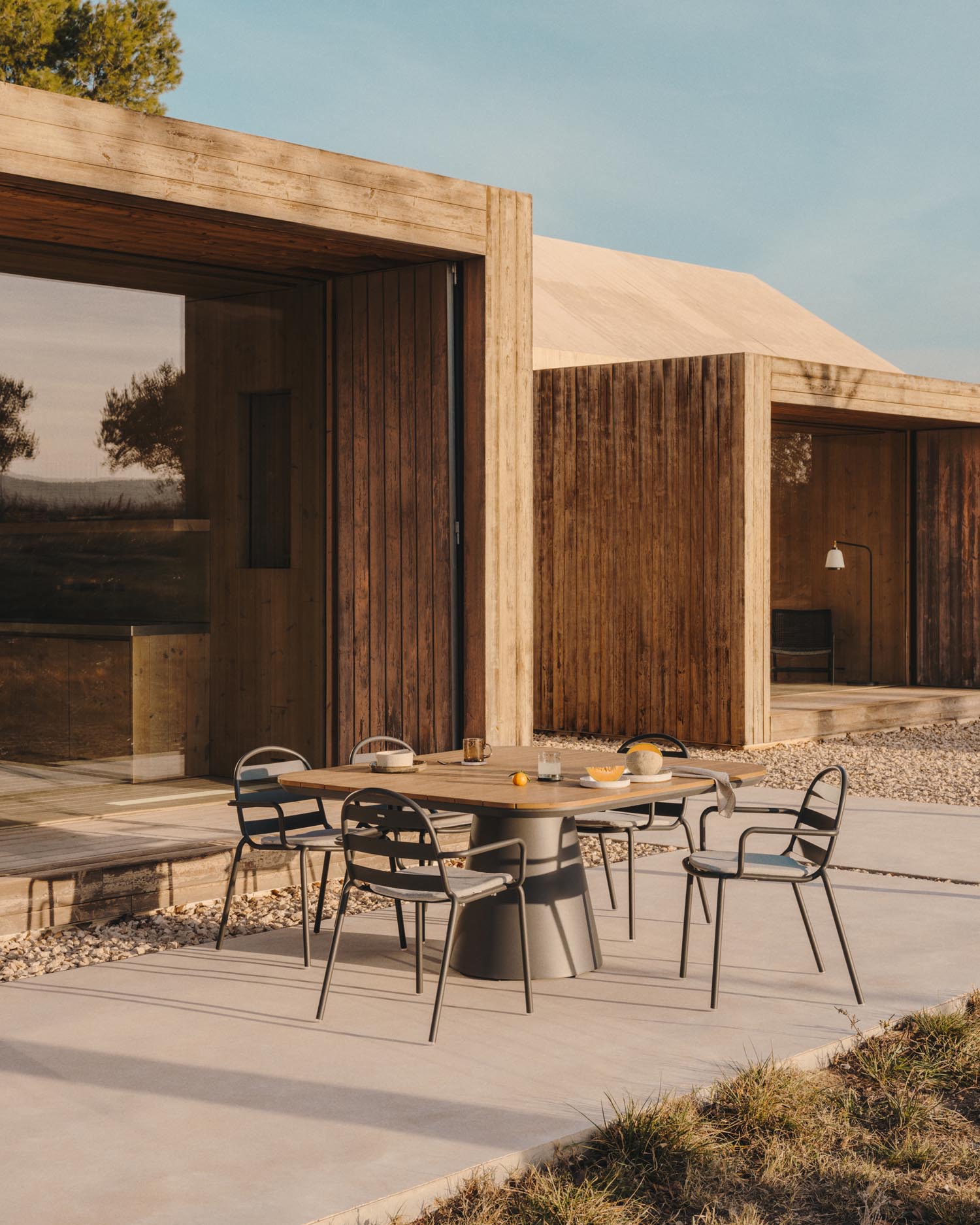 Entdecke den Tudons Outdoor-Tisch von Kave Home: 148x148 cm, wetterfestes Aluminium, stilvolles graues Design, nachhaltige Teakholzplatte für gesellige Momente.