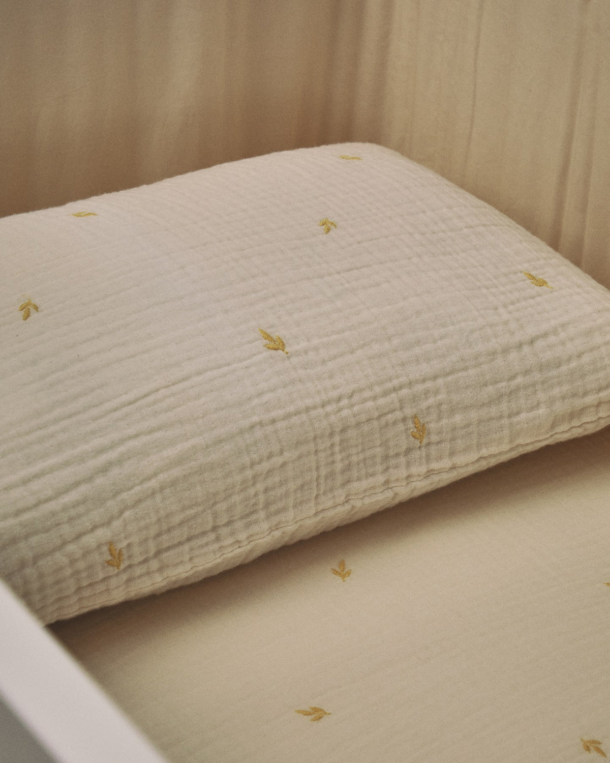 Bettbezug und Kopfkissen aus ecrufarbener Baumwoll-Doppelgaze mit aufgestickten Blättern, für Babybett, Set Dorani von Kave Home.