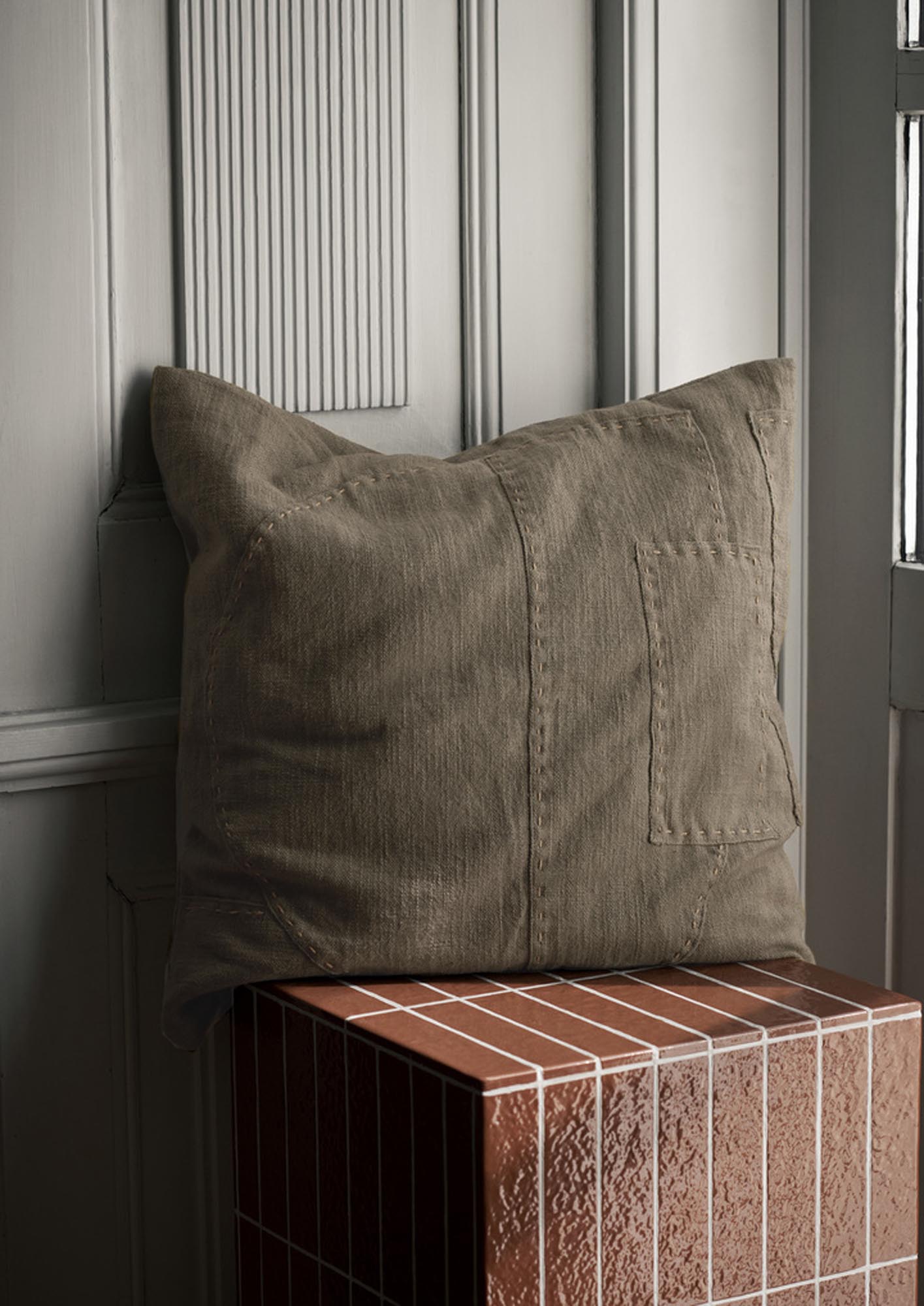 Elegantes Darn Kissen in dunklem Taupe, stilvoll drapiert auf einem modernen Sofa, ideal für gemütliche Wohnräume.