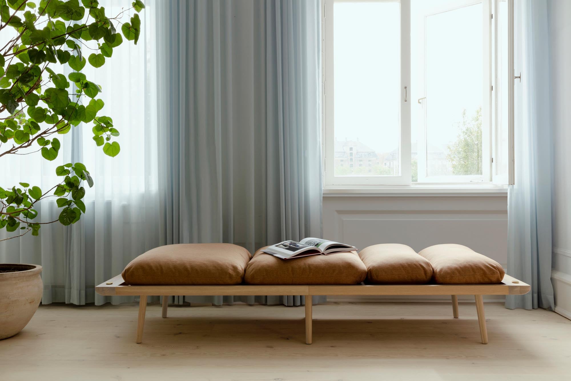 Das Lounge Around Daybed von Umage ist ein multifunktionales Möbelstück mit nordischem Design, hochwertigen Materialien und praktischem Zubehör wie Lampenständer und Beistelltisch.
