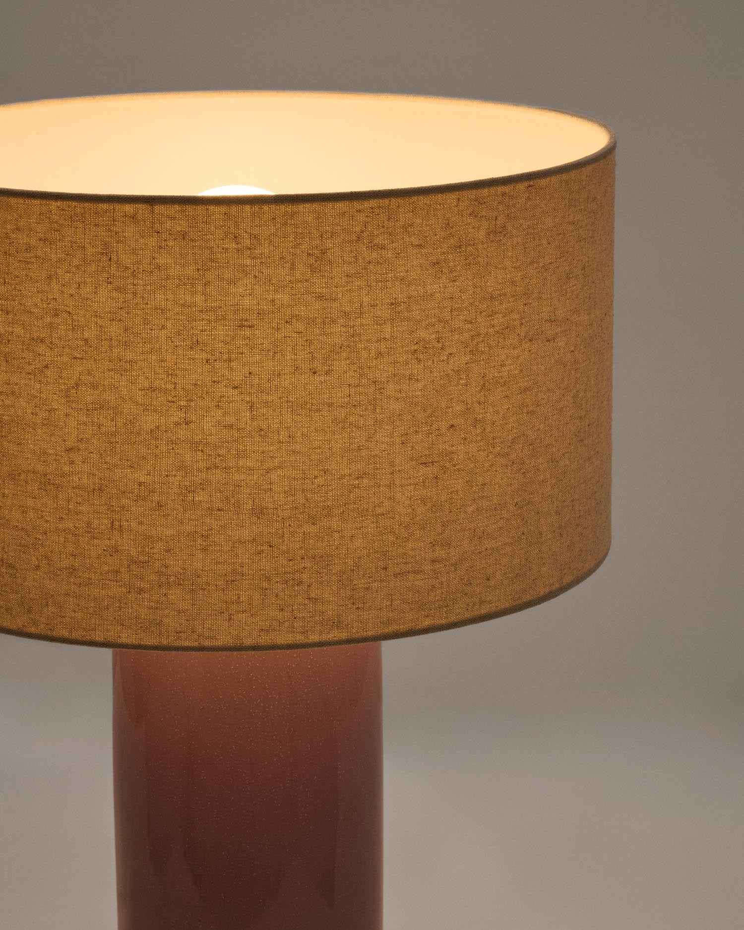 Die Tischlampe Toneric von Kave Home kombiniert eleganten lila Keramiksockel mit einem beigen Baumwollschirm und schafft so eine stilvolle Lichtquelle für jeden Raum.