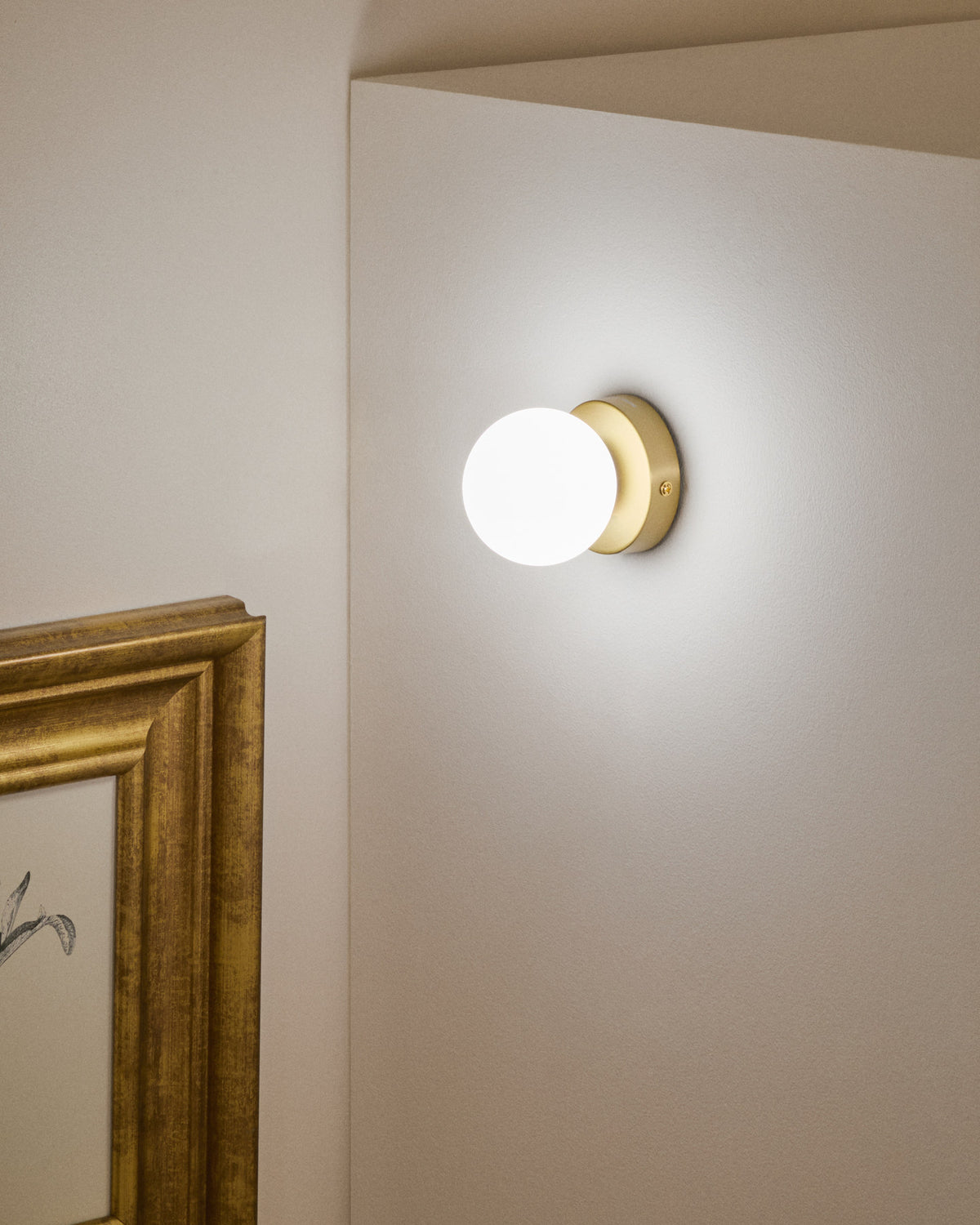 Wandleuchte Brisia aus Metall mit gebürstetem Messing-Finish und einer mattierten Glaskugel Ø 8 cm in Gold präsentiert im Onlineshop von KAQTU Design AG. Wandleuchte ist von Kave Home
