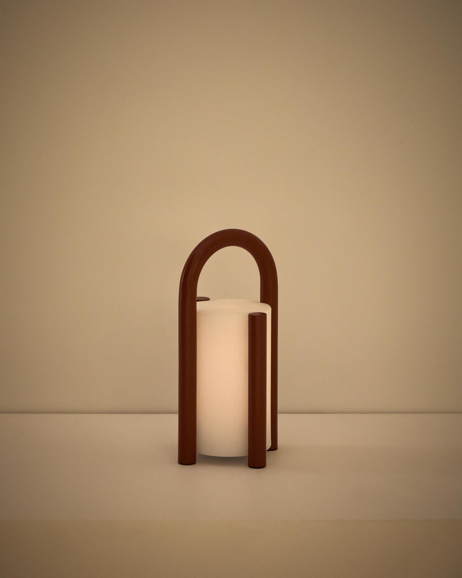 Kleine, stilvolle Tischlampe Leros aus robustem Polyethylen und terrakottafarbenem Stahl, ideal für gemütliche Outdoor-Atmosphäre.