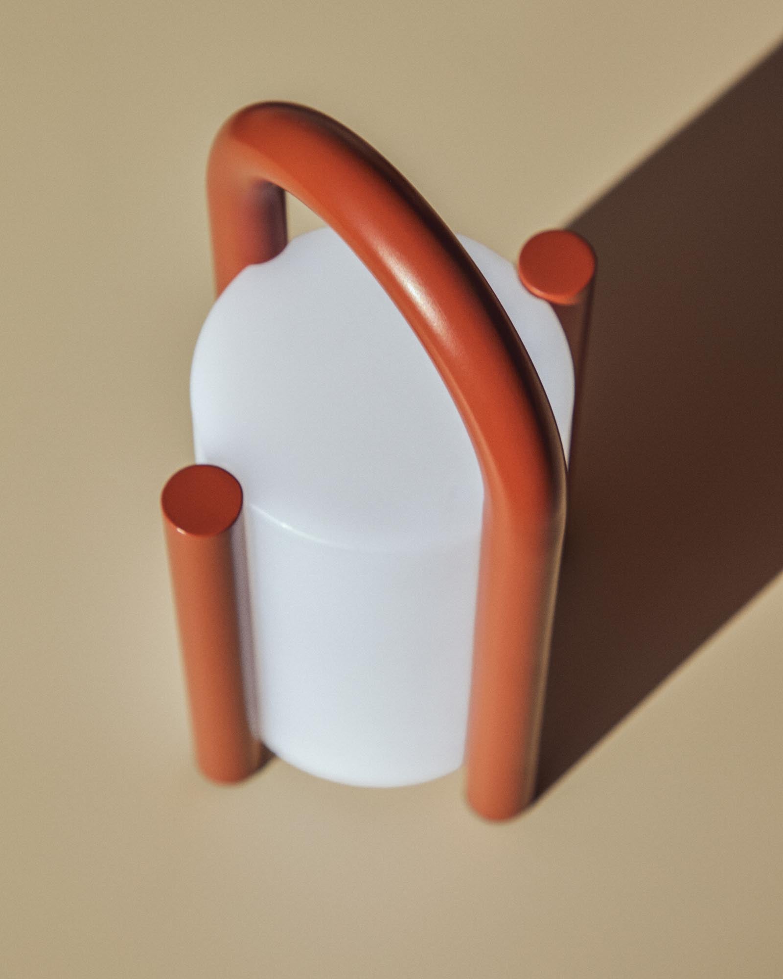 Kleine, tragbare Tischlampe Leros aus robustem Polyethylen und stilvollem terrakottafarbenem Stahl, perfekt für stimmungsvolle Abende im Freien.