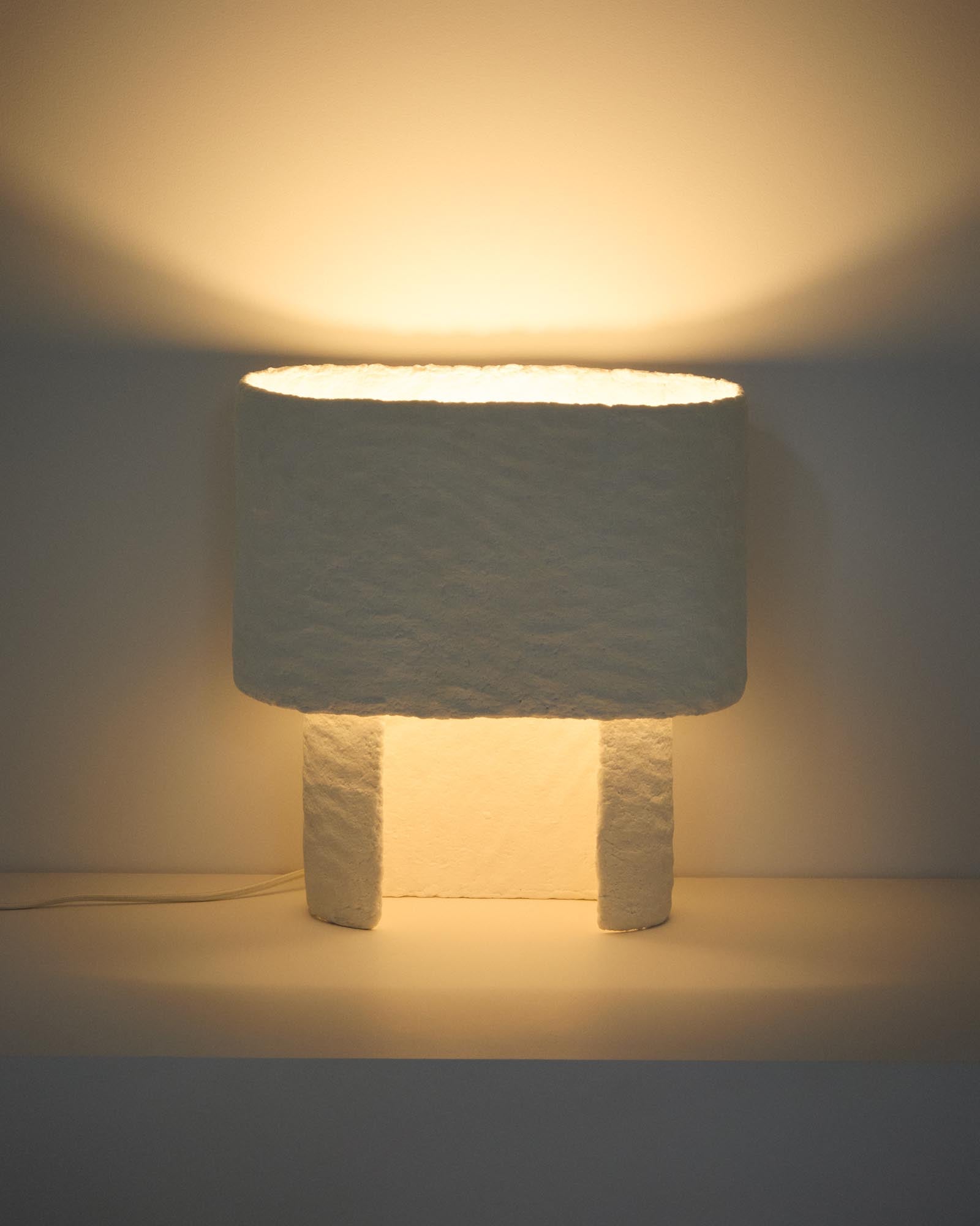 Moderne Tischlampe Bedala aus leichtem Pappmaché in Weiß, perfekt für kreative Beleuchtung und einladende Wohnräume.