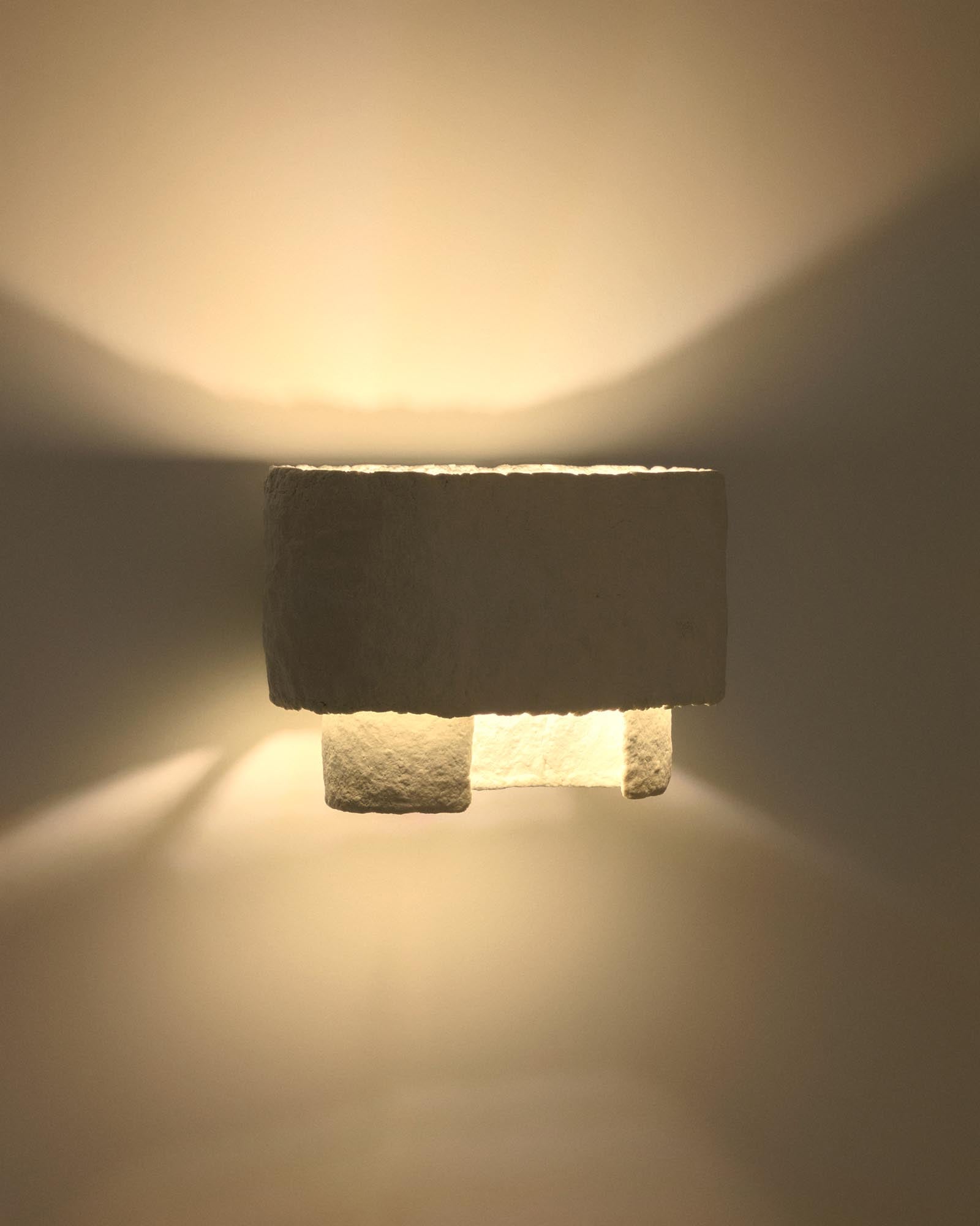 Moderne Wandleuchte Bedala aus leichtem, weißem Pappmaché, perfekt für kreative Raumgestaltungen und stimmungsvolle Lichtakzente.
