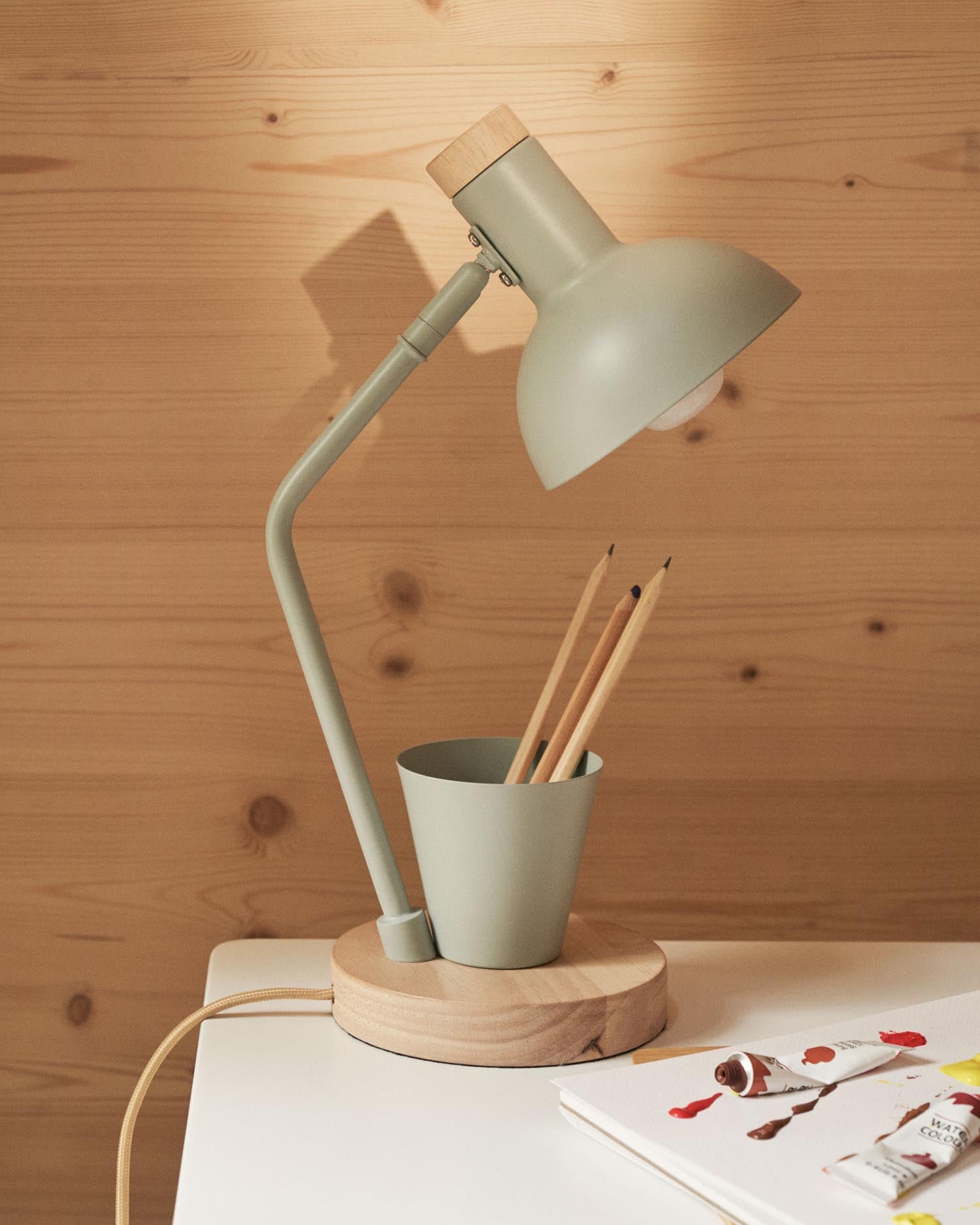 Entdecke die Katia Schreibtischlampe von Kave Home: eine elegante Kombination aus Holz und grünem Metall, perfekt für Kinderzimmer und stilvolle Akzente.