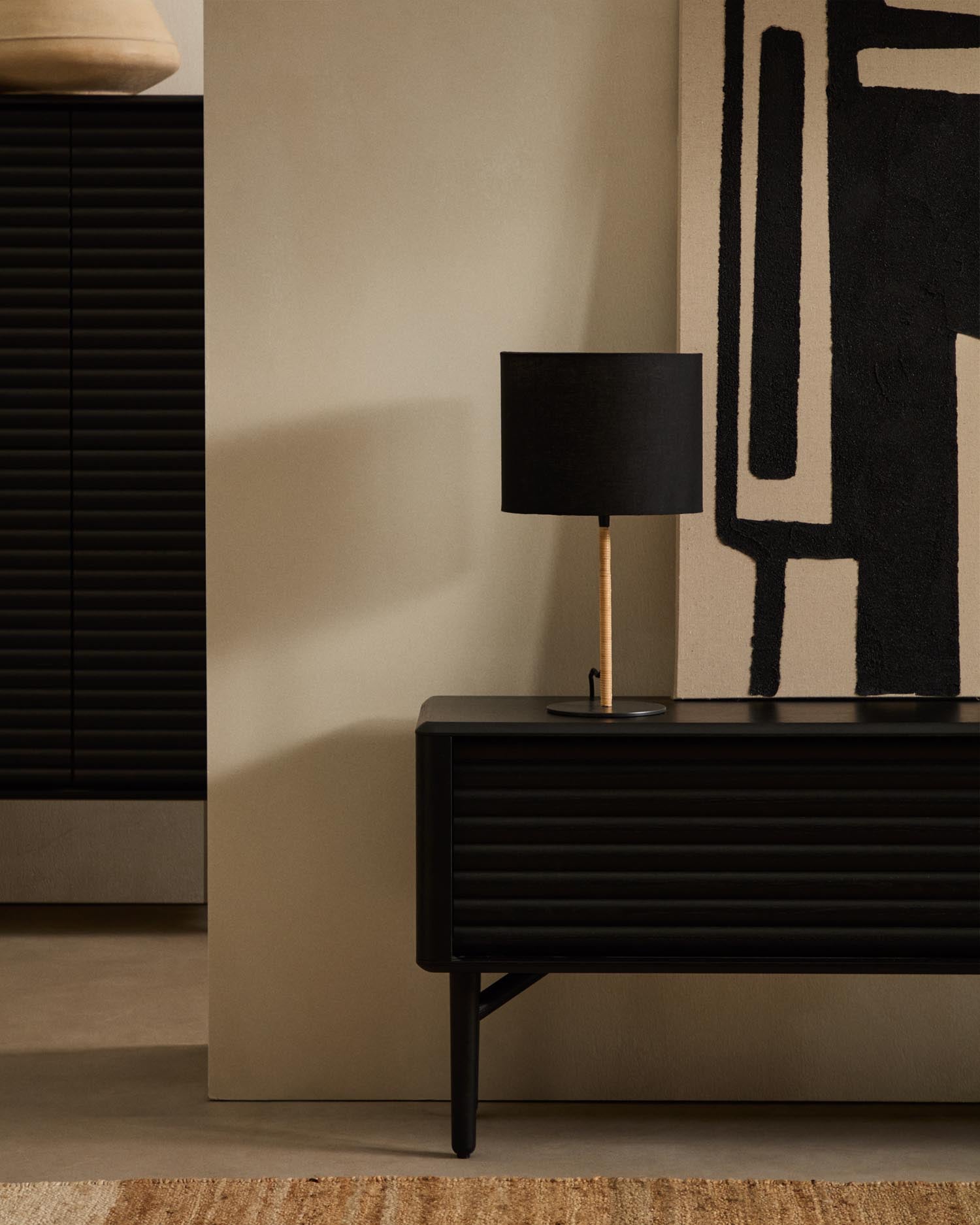 Die Pina Tischlampe von Kave Home kombiniert edles Metall und handgeflochtenes Rattan mit einem eleganten Baumwollschirm für ein warmes Ambiente.