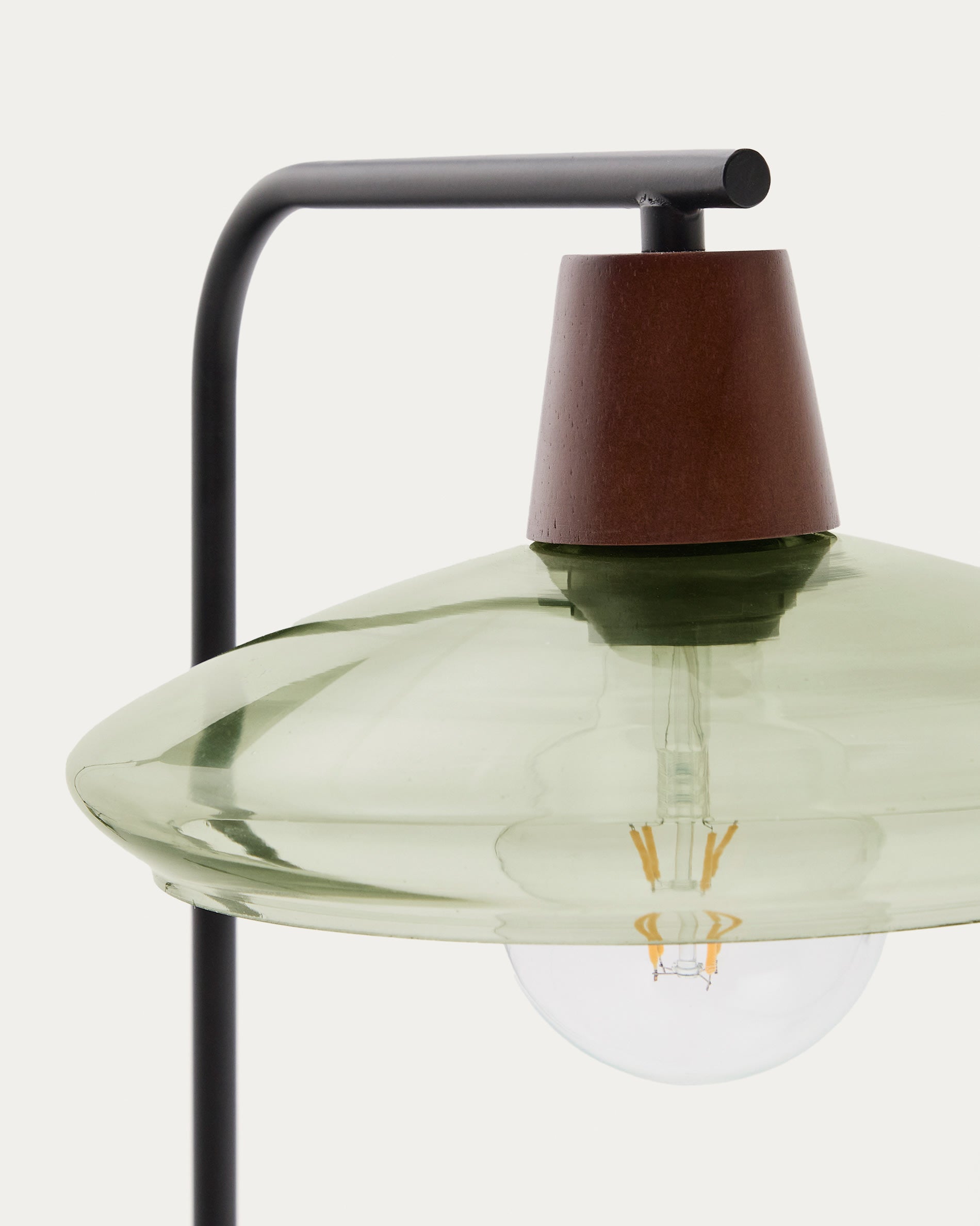 Entdecken Sie die Silex Tischleuchte von Kave Home: Elegante Metallbasis, beruhigendes grünes Glas und warmes Nussbaumfurnier für zeitgemäße Wohnakzente.