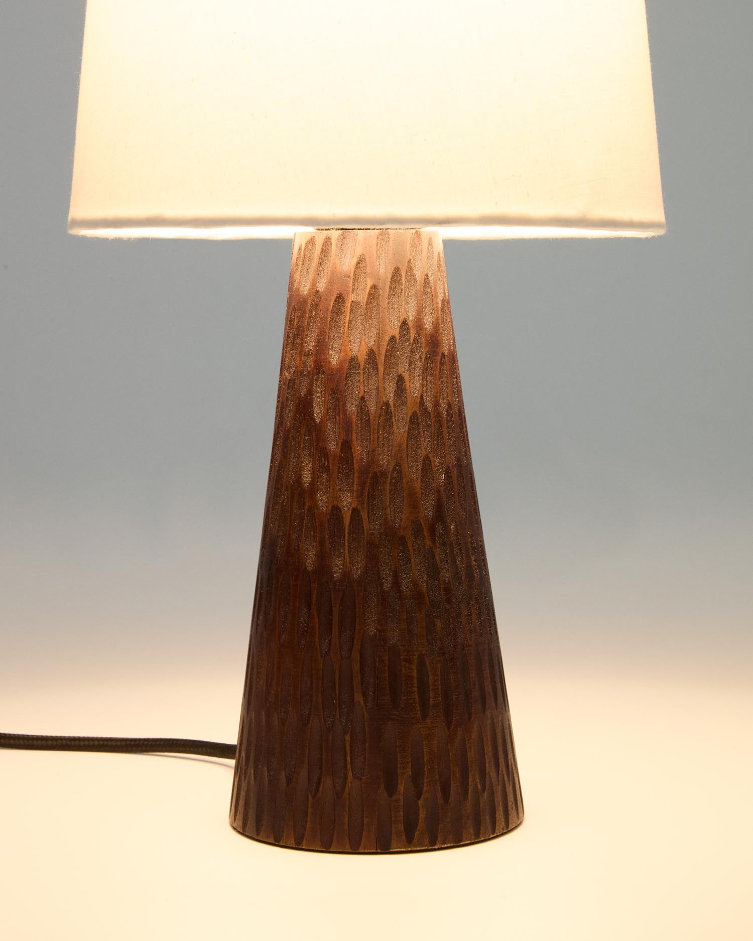 Die Tischleuchte Amire von Kave Home aus edlem Massivholz mit dunklem Finish bringt stilvolle Eleganz und Gemütlichkeit in Ihr Zuhause.