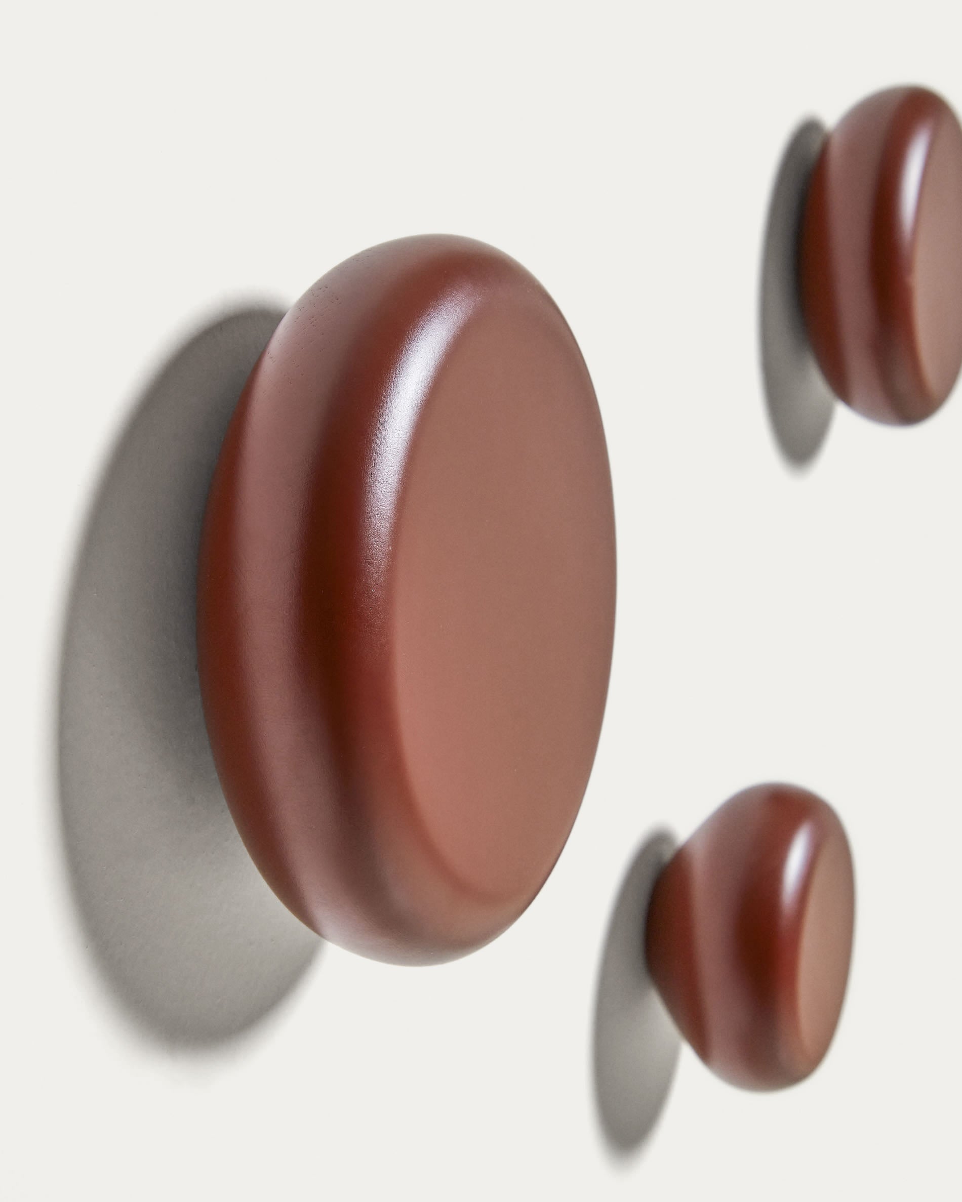 Set aus 3 stilvollen Wandhaken aus massiver Buche mit weinrotem Finish von Kave Home. Ideal für Flur, Schlafzimmer und Badezimmer.