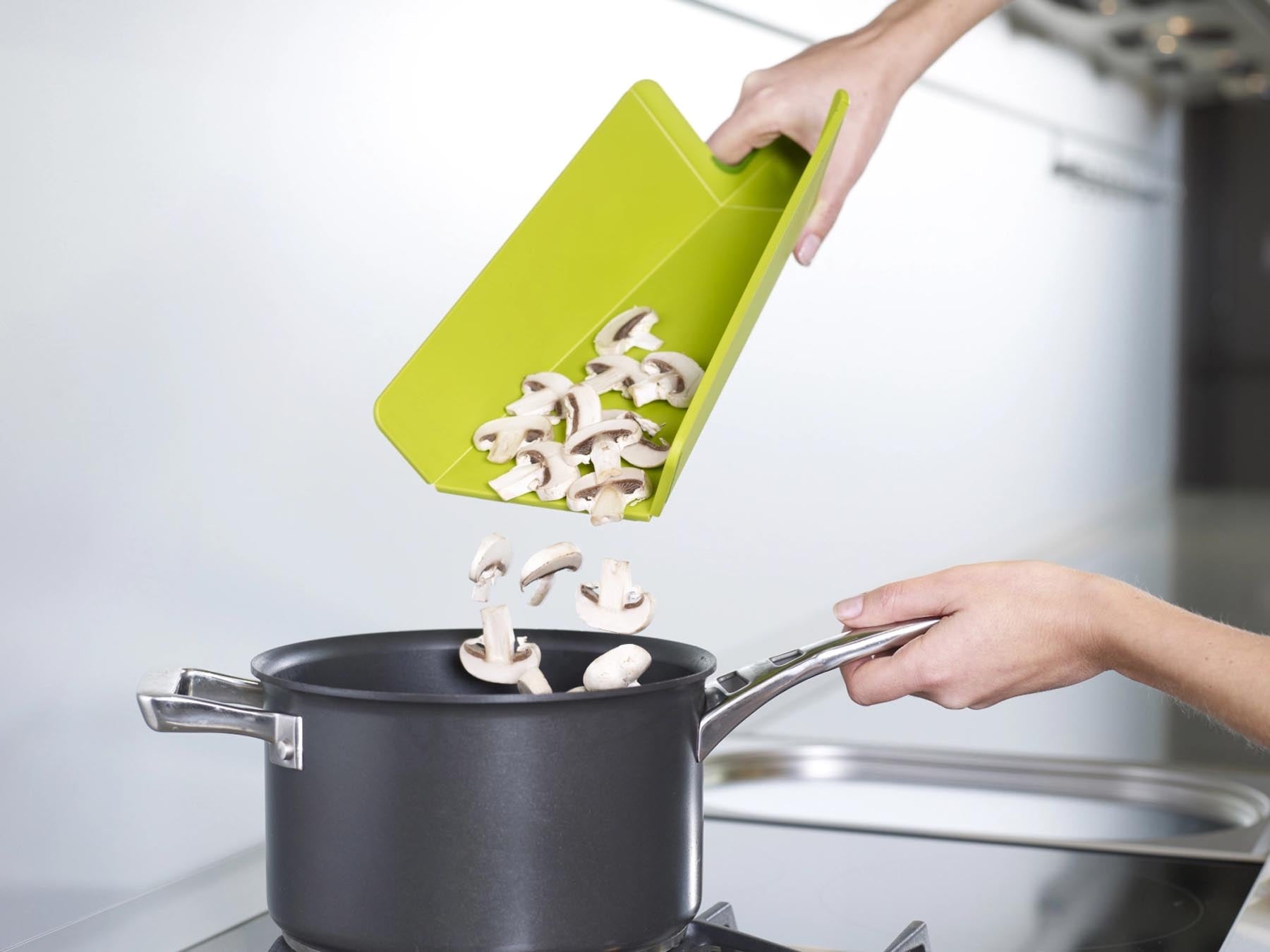 Chop2pot Plus Schneidebrett in lebhaftem Grün: innovatives Design mit klappbaren Kanten für müheloses Übertragen von Zutaten.