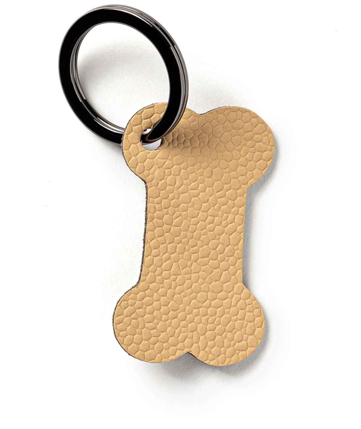 Beiger Schlüsselanhänger in Form eines Hundeknochens, Masse 7 x 5 x 0.2 cm, hergestellt von MiLLE W NORDISK DESIGN, Ansicht auf hellem Hintergrund.