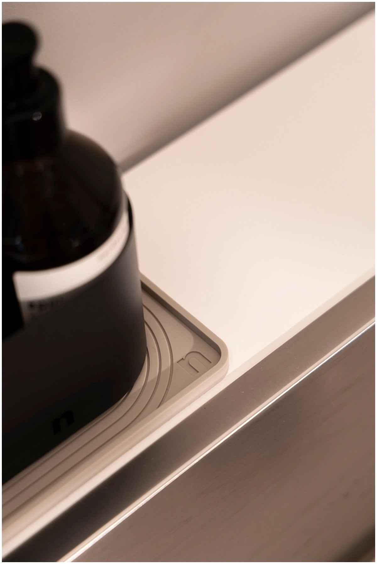 Beige Abtropfmatte aus Silikon, 28x10 cm, mit strukturierter Oberfläche und nordischem Bogenmuster, liegend auf einer Küchenarbeitsfläche.
