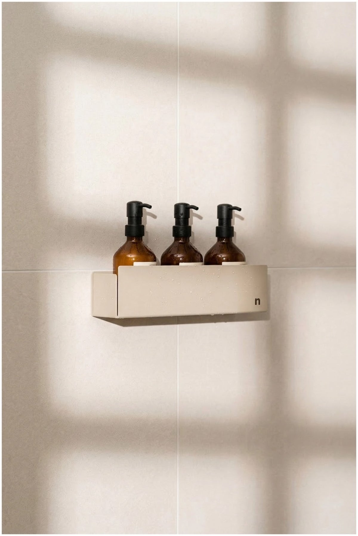 Beige Duschablage aus Aluminium mit pulverbeschichteter Oberfläche und integrierter Ablaufrinne, montiert an einer Duschkabinenwand.