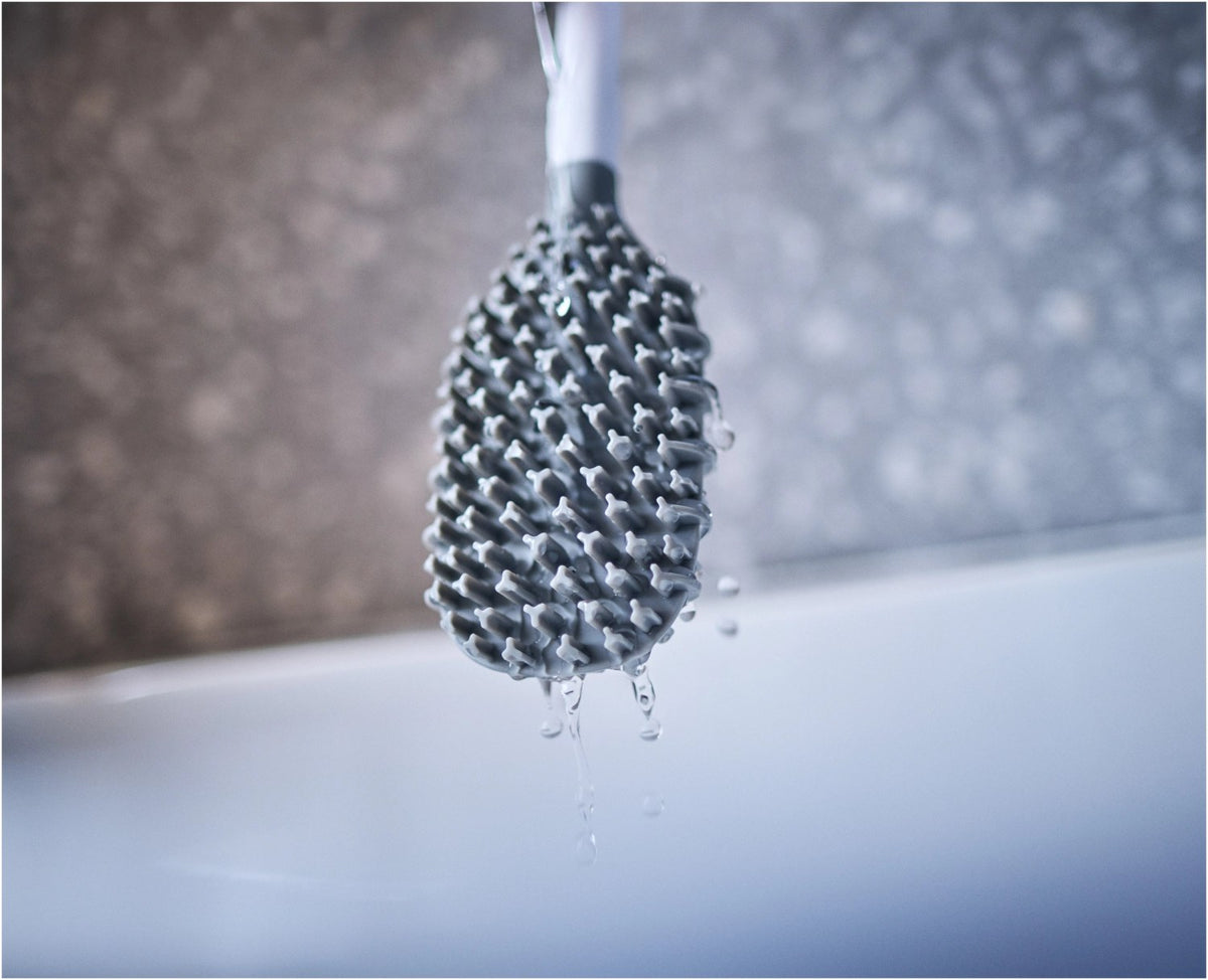 Weisse WC-Bürste Flex TriBlade von Joseph Joseph mit passendem geschlossenem Halter, schlanke Form, glänzende Oberfläche, freistehend im Badezimmer.