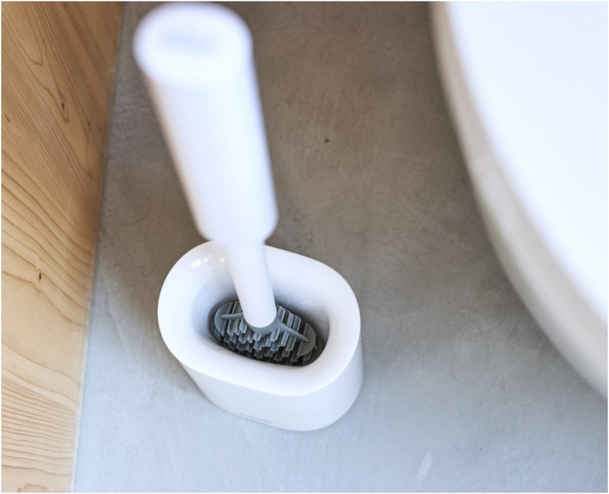 Weisse WC Bürste mit dreifach beklingten Borsten und passendem kompaktem Halter, glänzende Oberfläche, schlanke zylindrische Form.