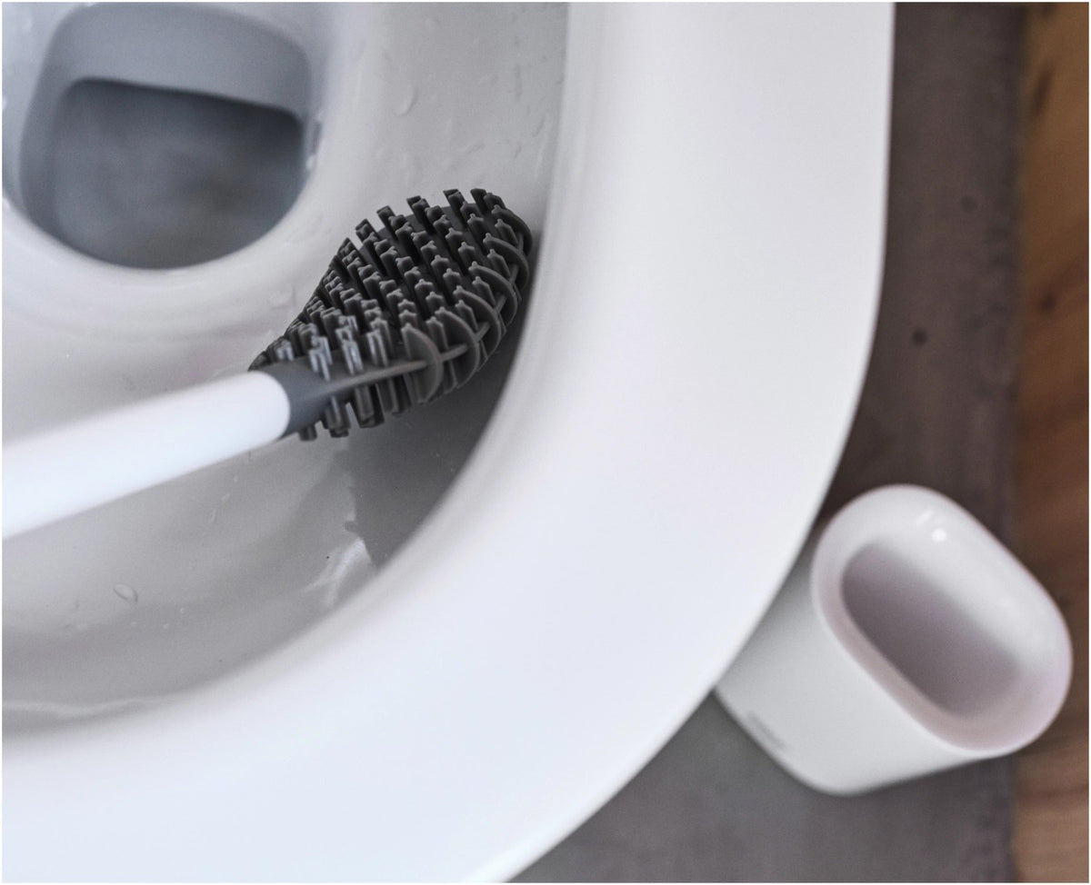 Weisse WC Bürste mit dreifach beklingten Borsten und passendem kompaktem Halter, glänzende Oberfläche, schlanke zylindrische Form.