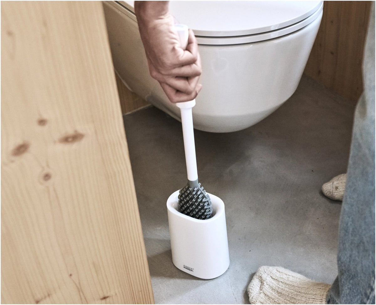 Weisse WC Bürste mit dreifach beklingten Borsten und passendem kompaktem Halter, glänzende Oberfläche, schlanke zylindrische Form.