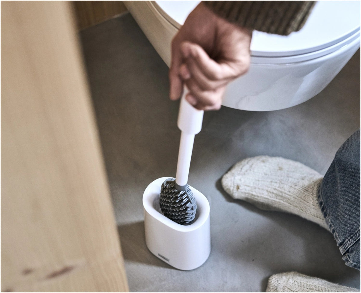 Weisse WC Bürste mit dreifach beklingten Borsten und passendem kompaktem Halter, glänzende Oberfläche, schlanke zylindrische Form.