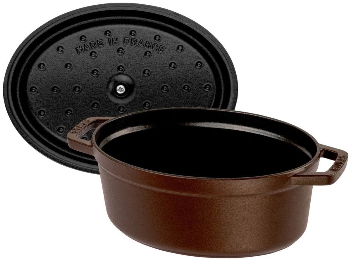 Ovale Staub Cocotte aus Gusseisen in brauner Emaille-Optik, 23 cm lang, mit Deckel und Tropfenstruktur auf der Innenseite.