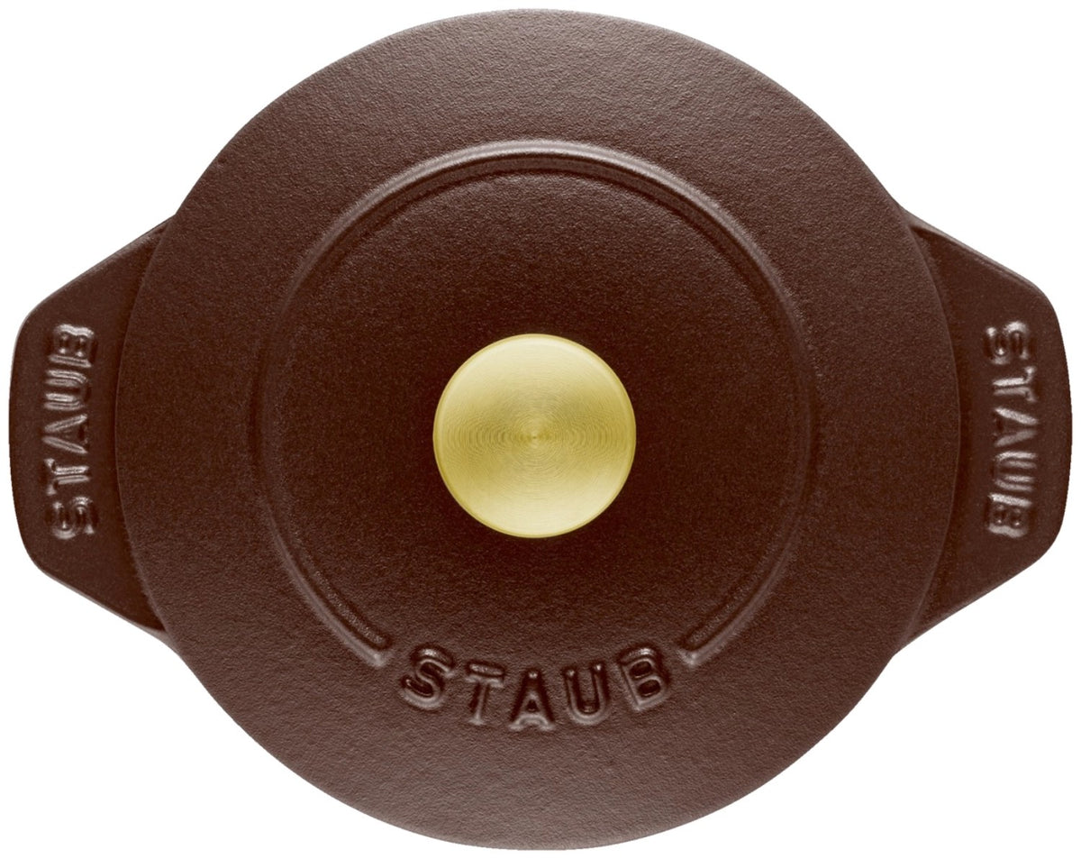 Braune Cocotte aus emailliertem Gusseisen von Staub, rund, mit Deckel, Grösse 20cm, Ansicht von schräg oben auf der Arbeitsfläche.