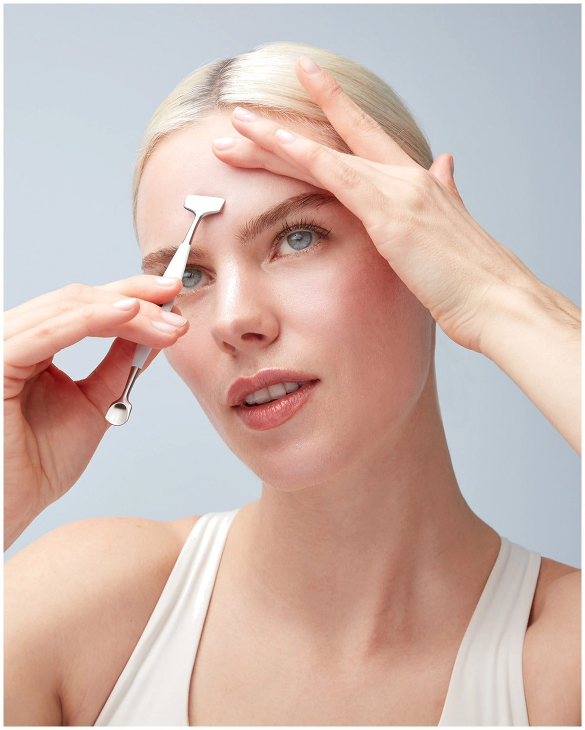 Silberfarbenes Facial Pore Refiner Tool aus Edelstahl mit zwei funktionalen Enden für die Gesichtspflege, liegend fotografiert.