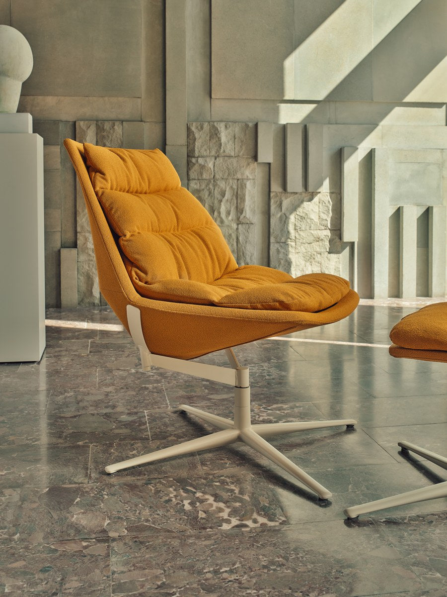 Ziegelroter Loungesessel mit gepolstertem Sitz, drapiertem Kissen und Aluminium-Drehfuss auf vier Sternbeinen, Frontalansicht.