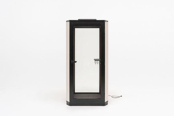 Ein-Personen-Akustikkabine Coda mit Glastür, Metall-Aussenwand in Dunkelgrün, gepolsterten Innenwänden und Deckenbeleuchtung.
