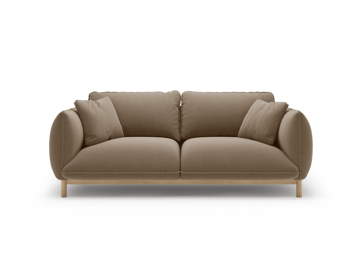 Ada 2er Sofa von Micadoni in Mandel beige mit gepolstertem Velours-Bezug, geschwungener Rückenlehne und sichtbaren Buchenholzbeinen.