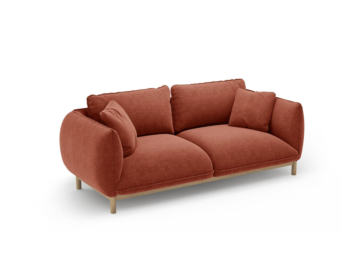 Ada 2er Sofa von Micadoni in Mandel beige mit gepolstertem Velours-Bezug, geschwungener Rückenlehne und sichtbaren Buchenholzbeinen.