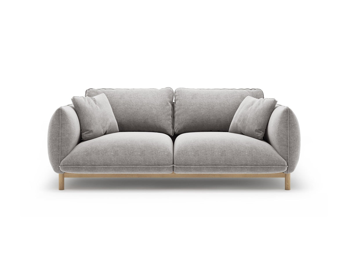 Ada 2er Sofa von Micadoni in Mandel beige mit gepolstertem Velours-Bezug, geschwungener Rückenlehne und sichtbaren Buchenholzbeinen.
