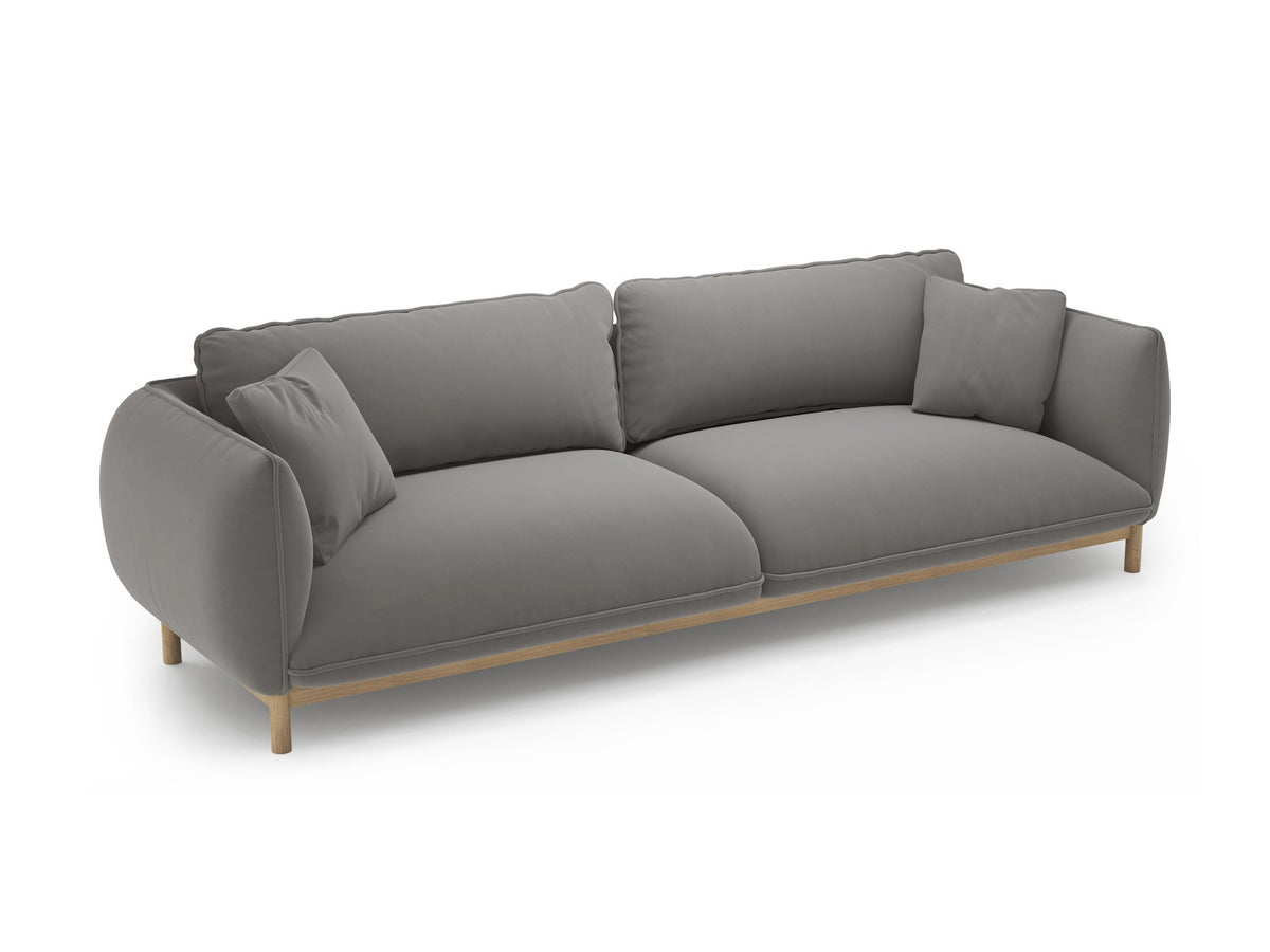Vierersofa Ada von Micadoni in Mandel beige mit Casino-Stoffbezug, gerundeten Armlehnen und sichtbarem Buchenholzgestell auf Holzbeinen.