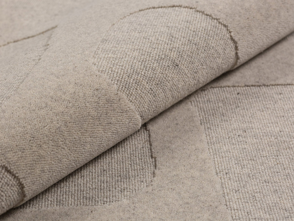 Hellgrauer rechteckiger Teppich Archipelagio von Micadoni aus 100% Wolle mit dichtem Flor und sauber verarbeiteten Kanten auf hellem Boden.