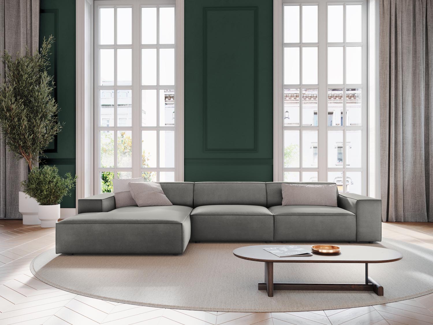 Elegantes, modulares Ecksofa Jodie Velour in sanftem Grau, ideal für stilvolle Wohnräume, präsentiert in einer einladenden Atmosphäre.