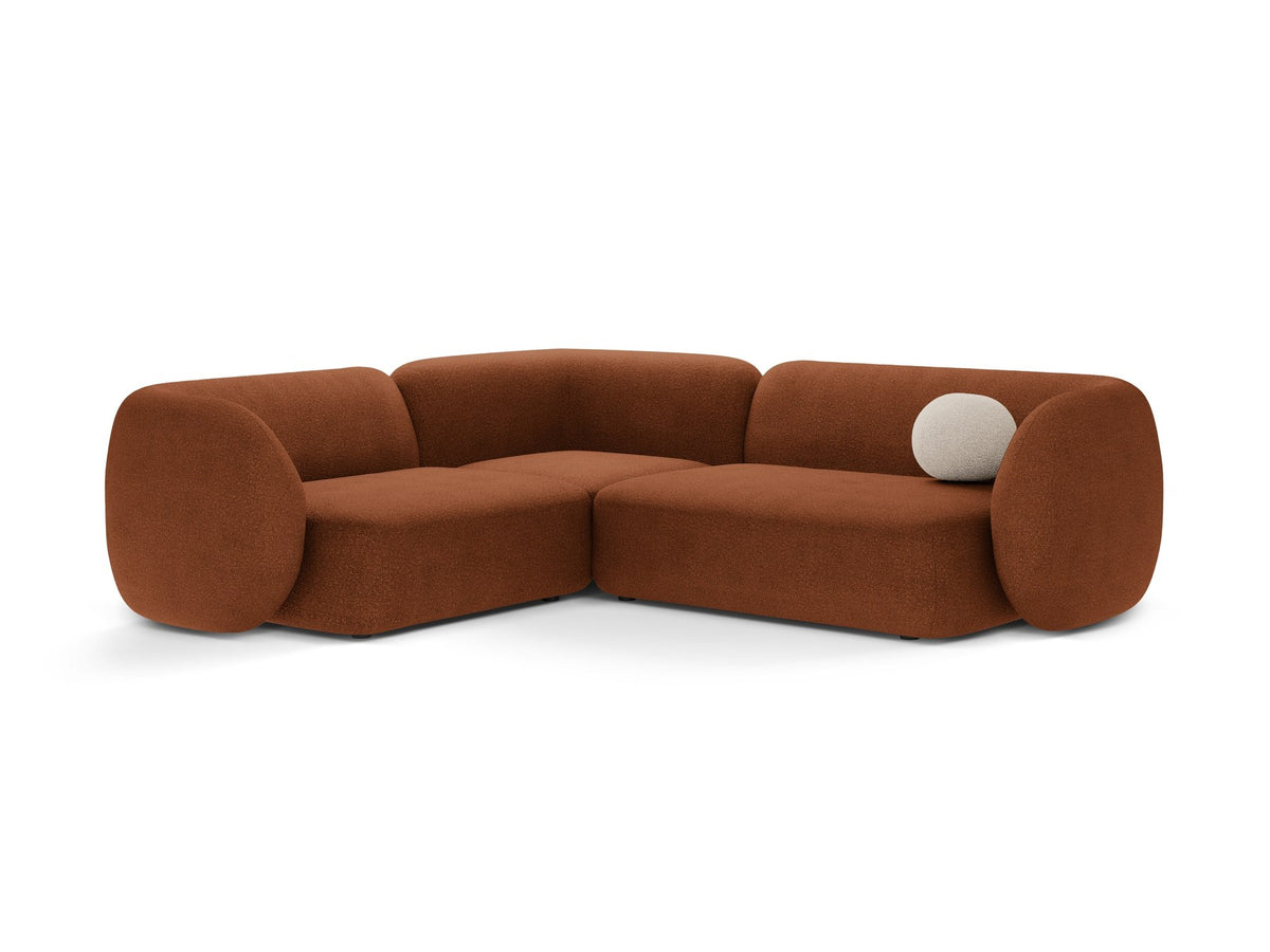 Weisses Ecksofa links Kate von Micadoni mit Bouclé-Stoff Baloo, schwarzen Kunststoffbeinen und niedriger Rückenlehne im Wohnraum.