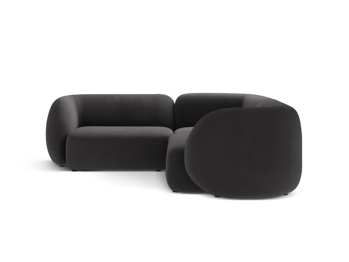 Weisses Ecksofa links Kate von Micadoni mit Bouclé-Stoff Baloo, schwarzen Kunststoffbeinen und niedriger Rückenlehne im Wohnraum.