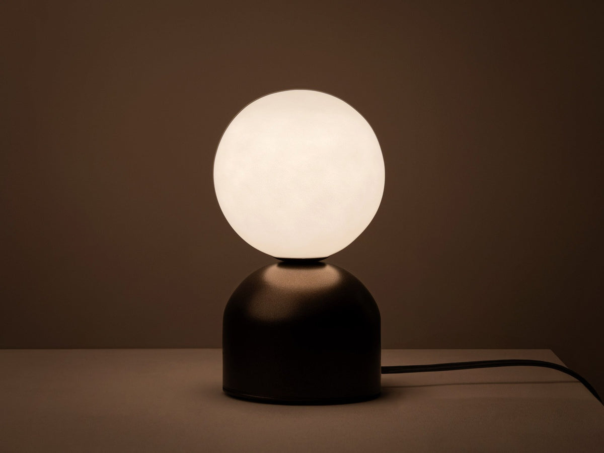Tischlampe Ely von Micadoni mit rundem Metallfuss und mattem Glasschirm in Beige, Höhe 21 cm, Breite und Tiefe je 12 cm.