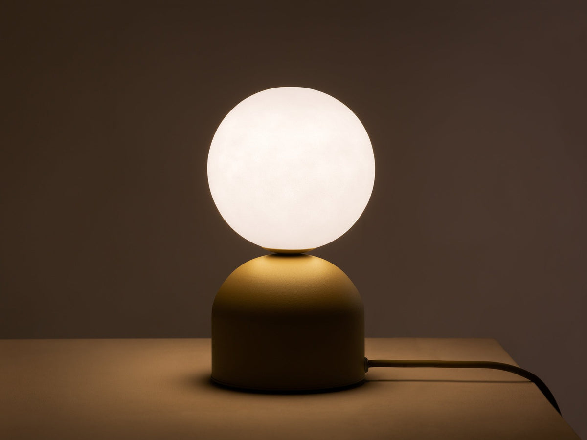Tischlampe Ely von Micadoni mit rundem Metallfuss und mattem Glasschirm in Beige, Höhe 21 cm, Breite und Tiefe je 12 cm.