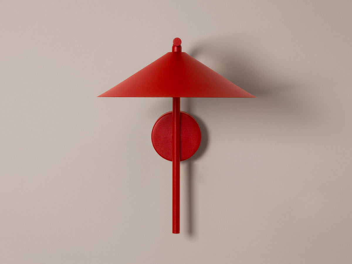 Wandlampe Nocte von Micadoni in Burgundfarben, konische Form aus mattem Metall, montiert an einer hellen Wand im Wohnraum.