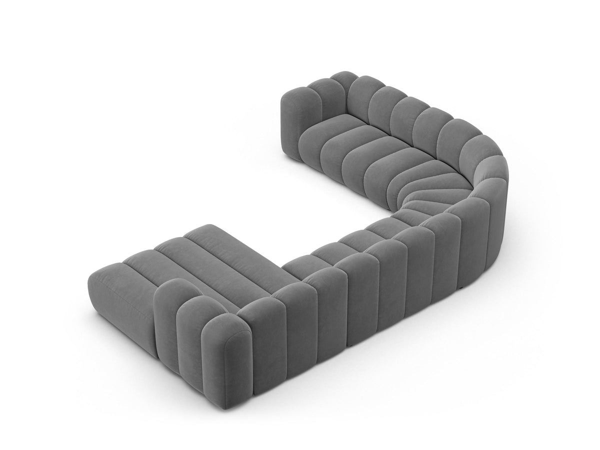 Foto eines modularen Ecksofas links in leichtem Beige aus Samtstoff Venus, mit schwarzen Kunststoffbeinen und breiter Sitzfläche.